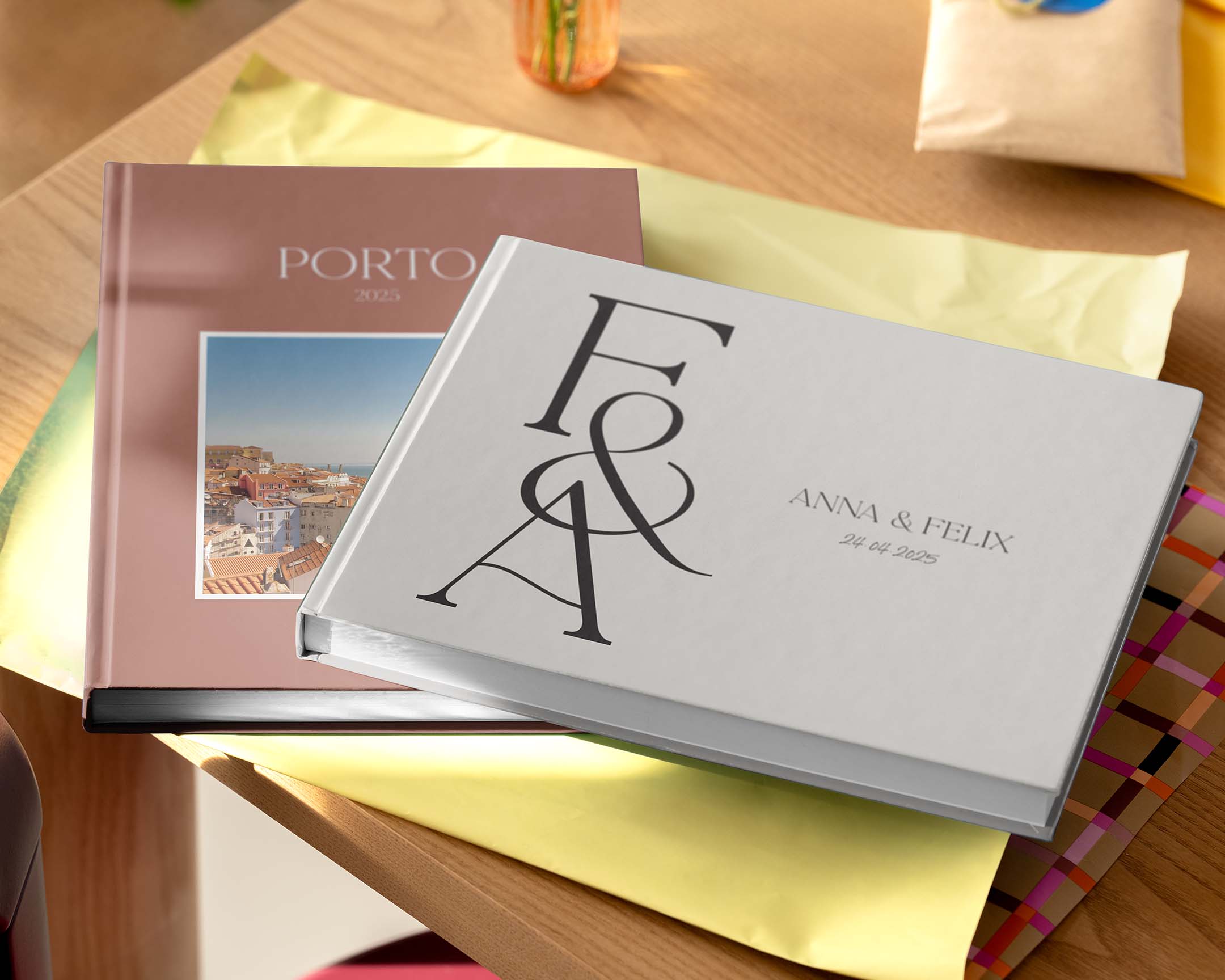 To personlige fotobøger i forskellige størrelser og designs, der vises på et bord.