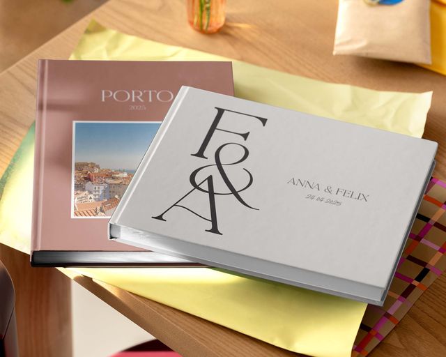 To personlige fotobøger i forskellige størrelser og designs, der vises på et bord.