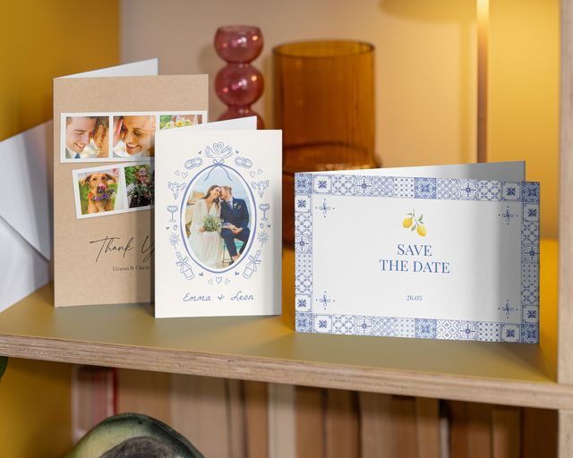 Tre bryllupsfotokort på en hylde: et "save the date"-kort og to takkekort.